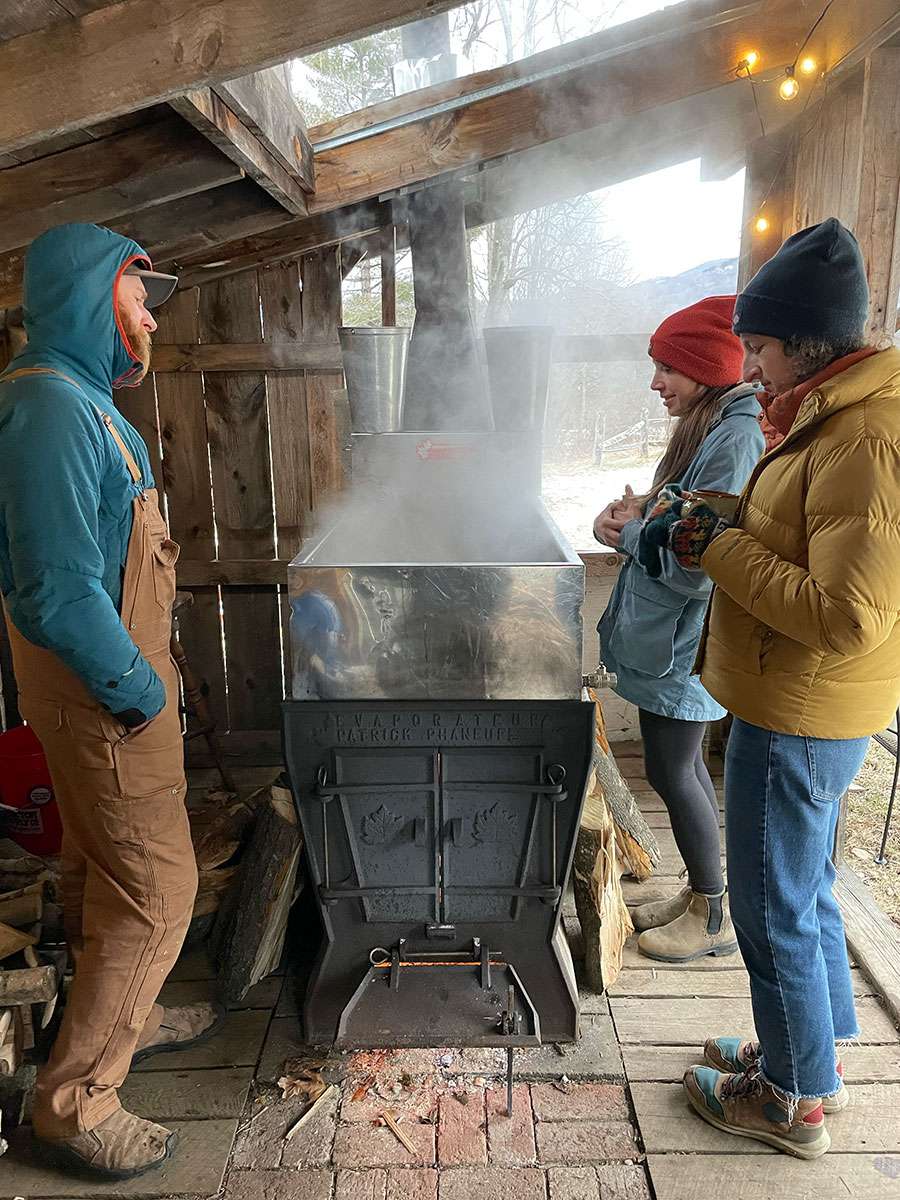 People gathered around a maple syrup evaporator