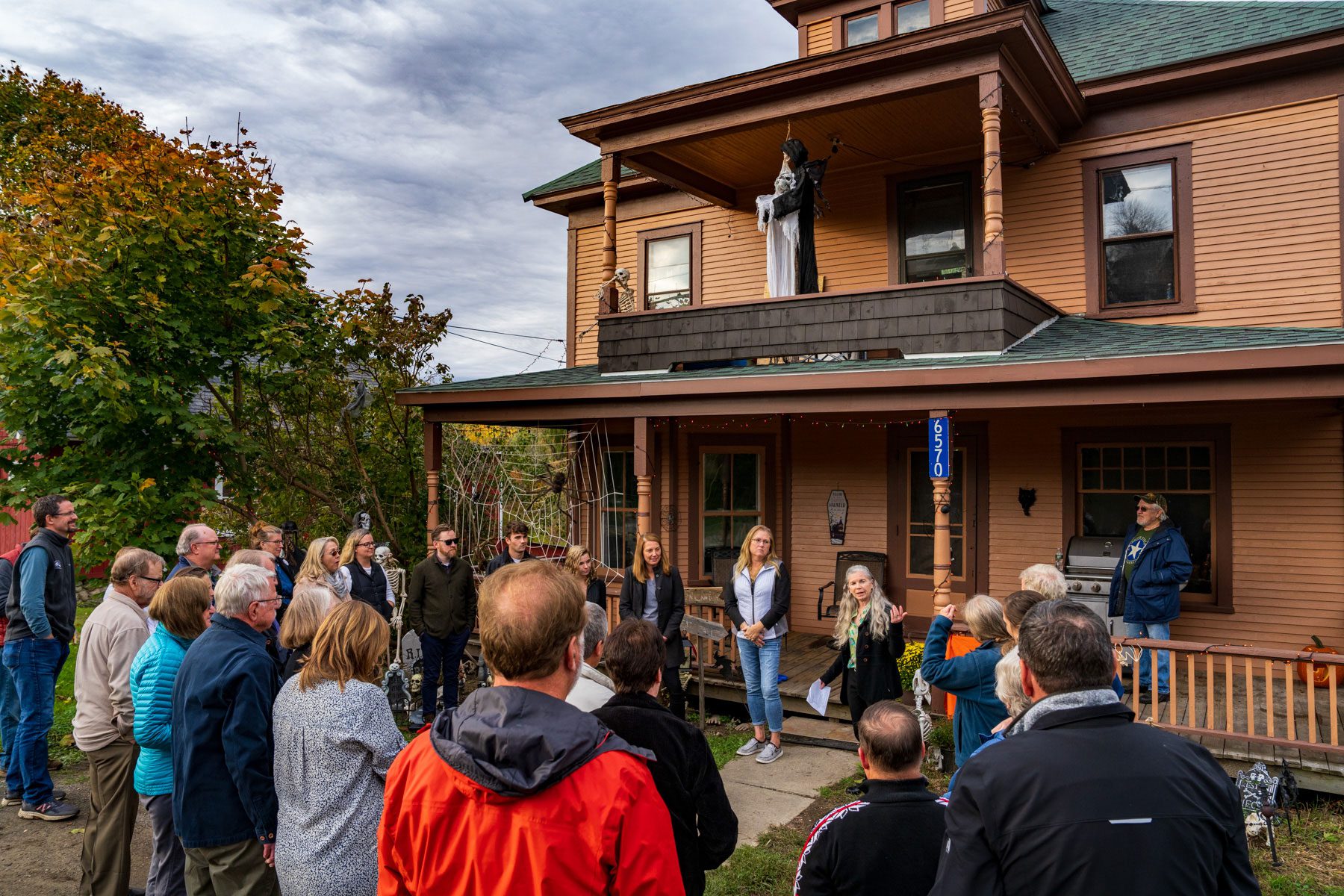 group of people standing in front of a brown house