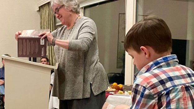 Author Amy Godine reads from her new book “The Black Woods” as a young reader follows along.