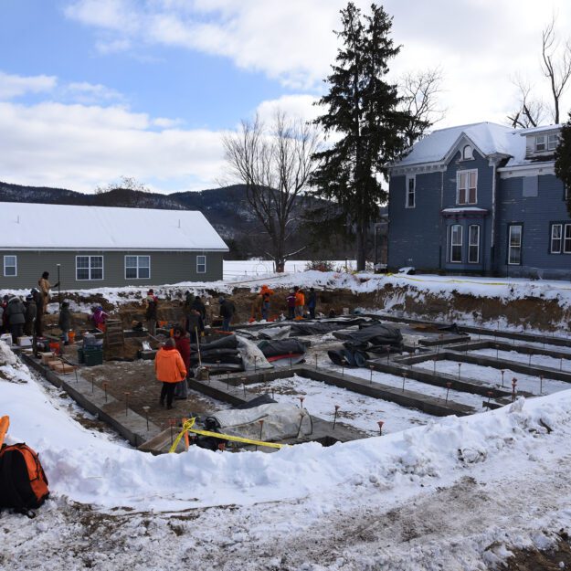 A dig site in the snow with volunteers