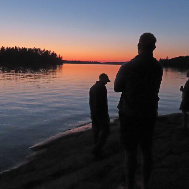 three men watching a sunset