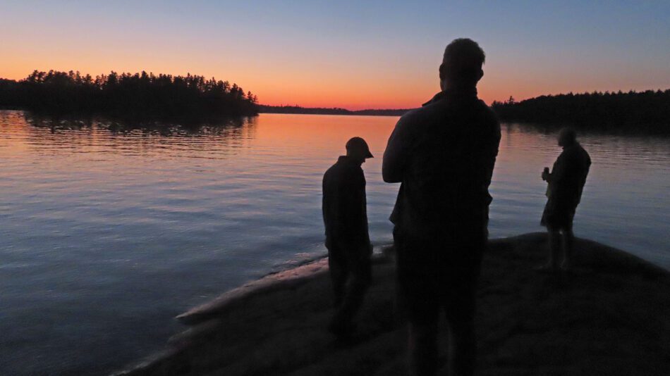 three men watching a sunset