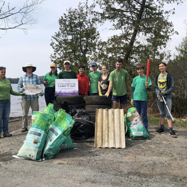 A group of young people celebrate Earth Day at a lake