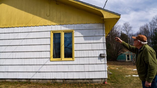 Greg Furness using a laser pointer showing black fungus on his house in Moriah