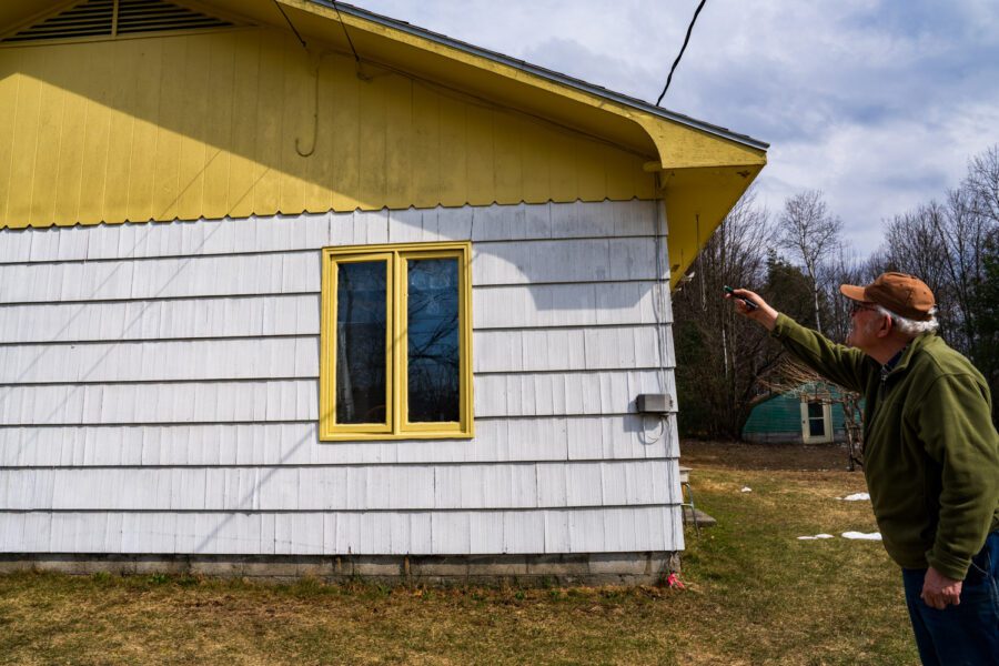 Greg Furness using a laser pointer showing black fungus on his house in Moriah