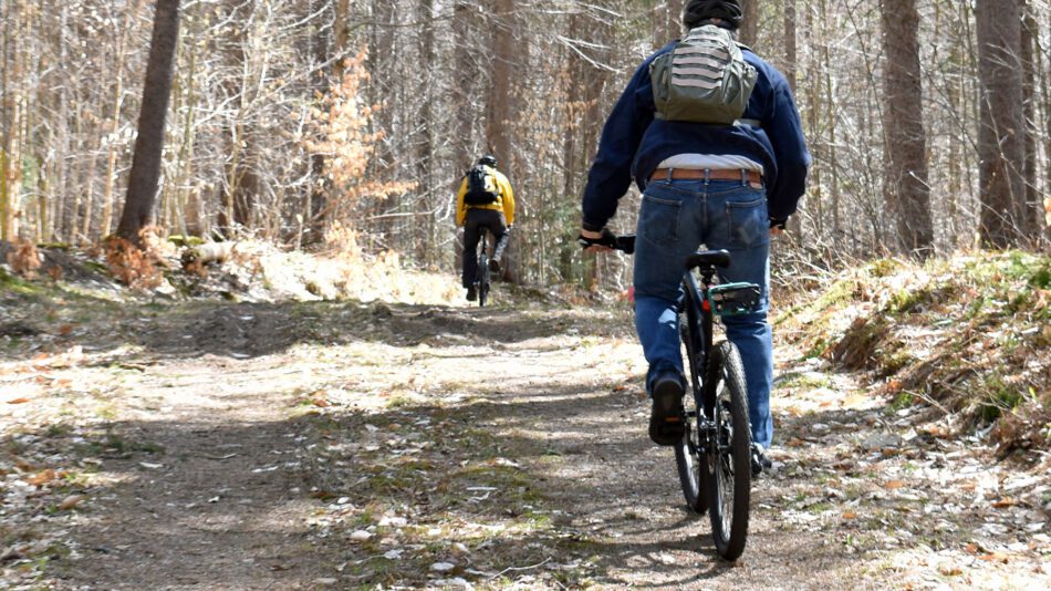 two men on bikes riding up a hill in Wanakena