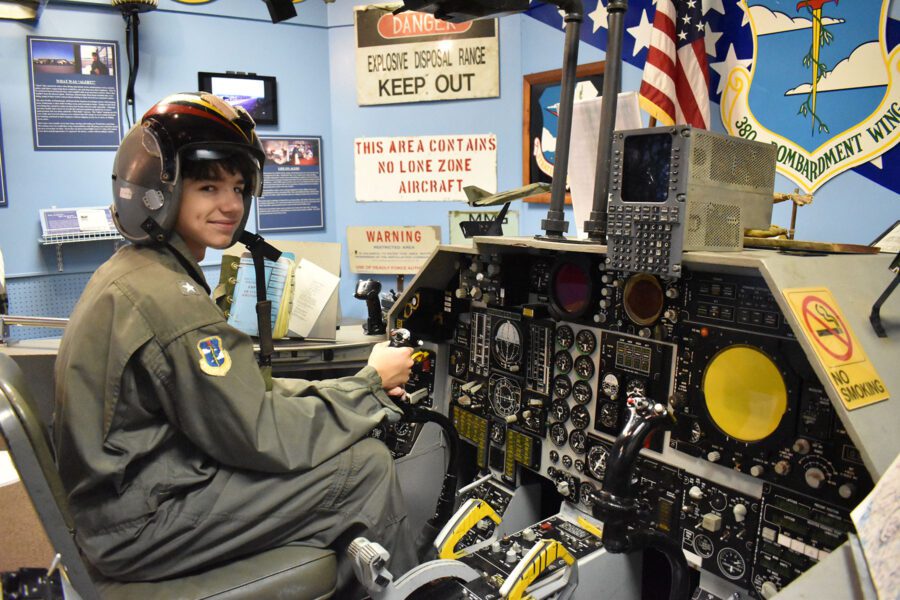 teen boy dressed as a military pilot site in a mock console