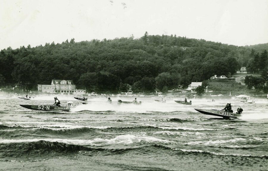 Black and white photo of speed boats racing on a wavy lake.