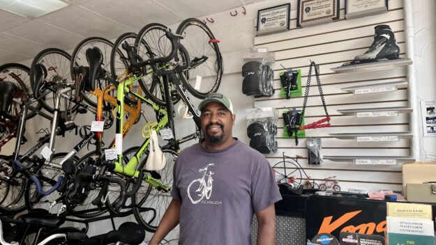 A man stands behind the counter of a bike shop in Saranac Lake, New York.