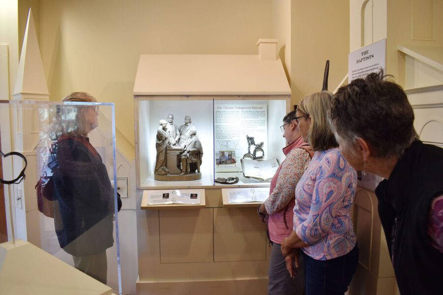 A group of retired teachers examines a display that includes information about the Chinese Underground Railroad of the 1880s.