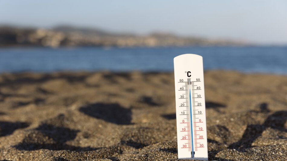 A thermometer showing high temperatures stuck in sand