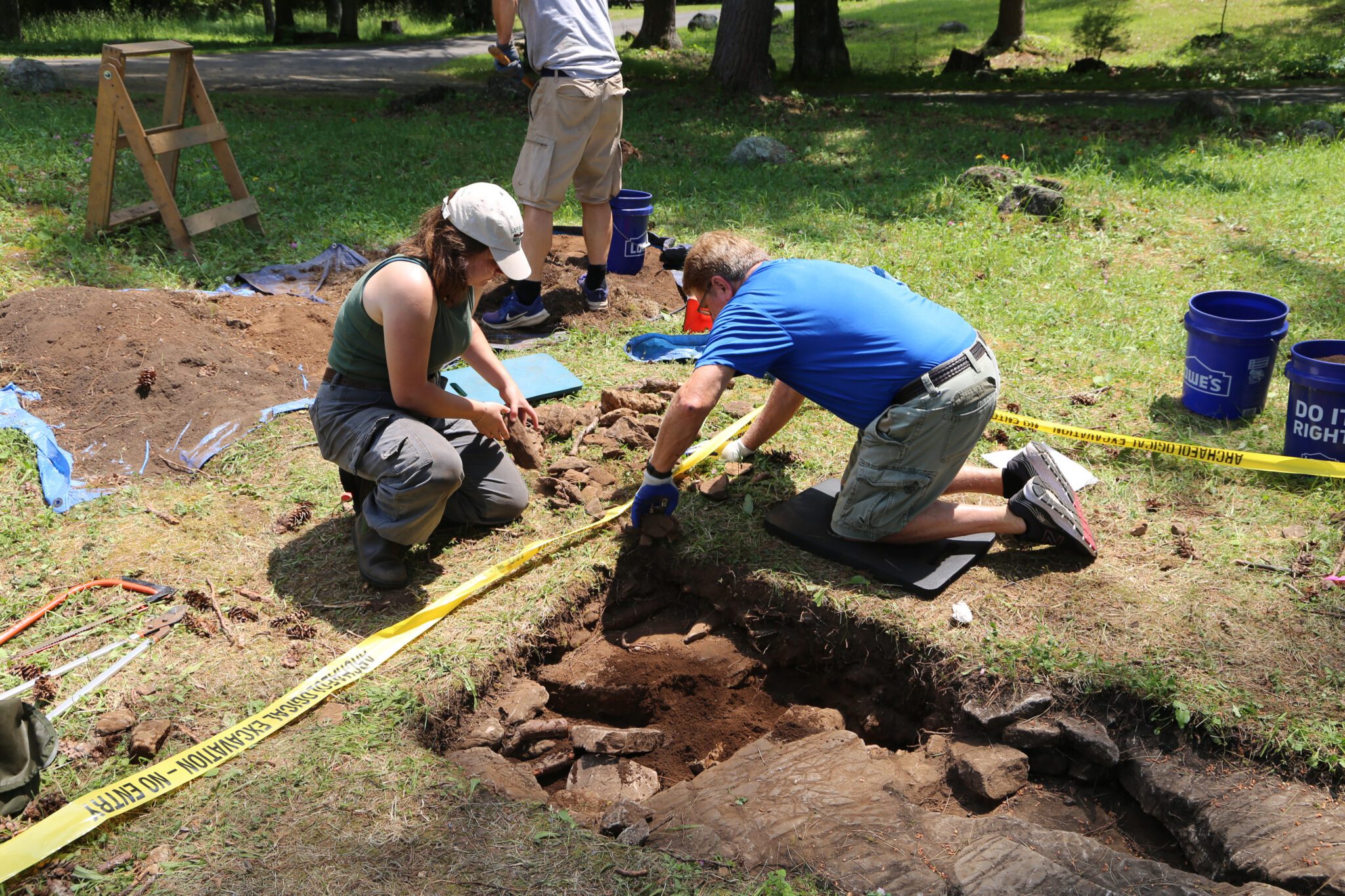 People begin to fill in an archaeological test pit at the Lake George Battlefield Park