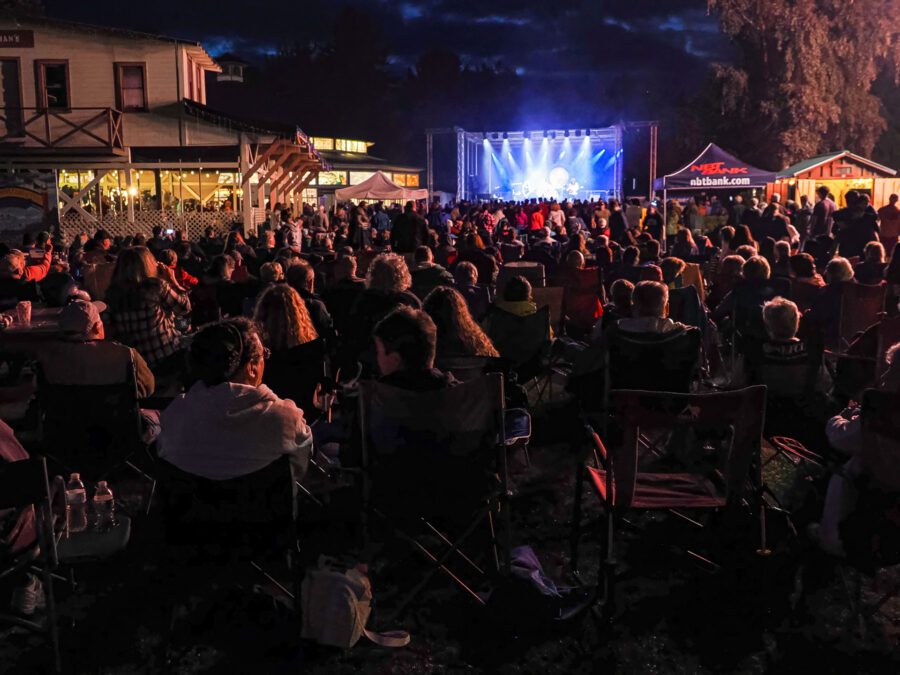 People in lawn chairs watch outdoor concert.