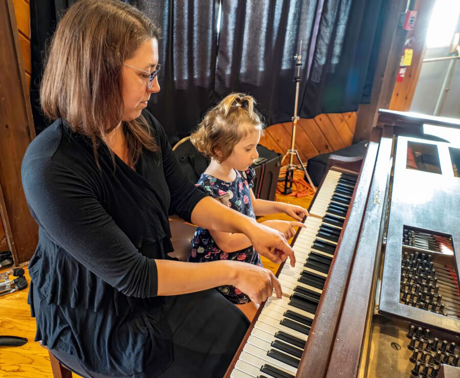 A woman and a child play piano together.