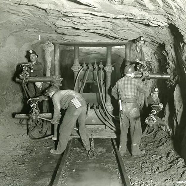 Black and white photo of miners working in an iron mine.