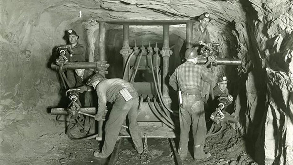 Black and white photo of miners working in an iron mine.