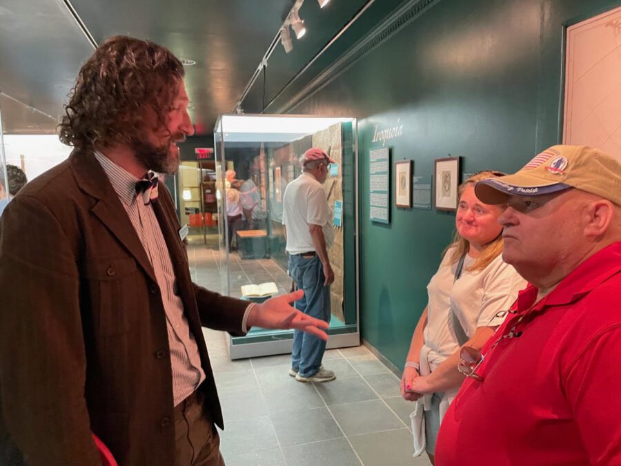 Man speaks to two museum visitors.