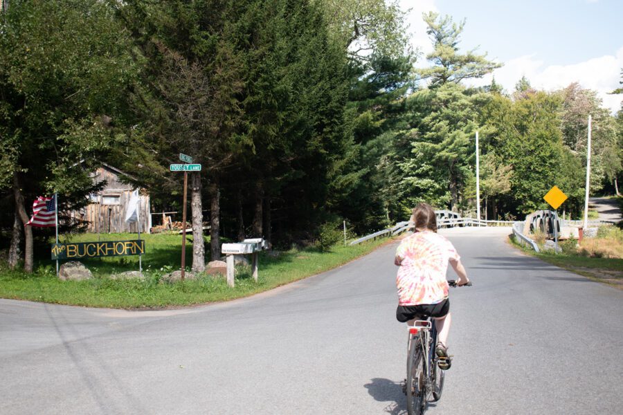 Woman in a tie-dye shirt biking on a road