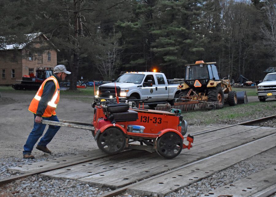 Man pushes red rail car.