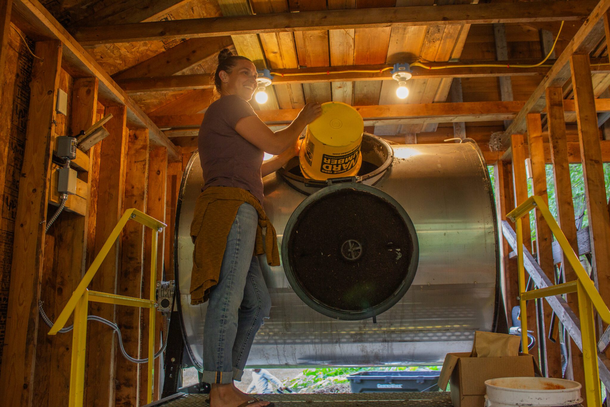 A woman puts compost into a tumbler