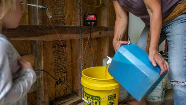 A woman pours human urine into a bucket to be composted