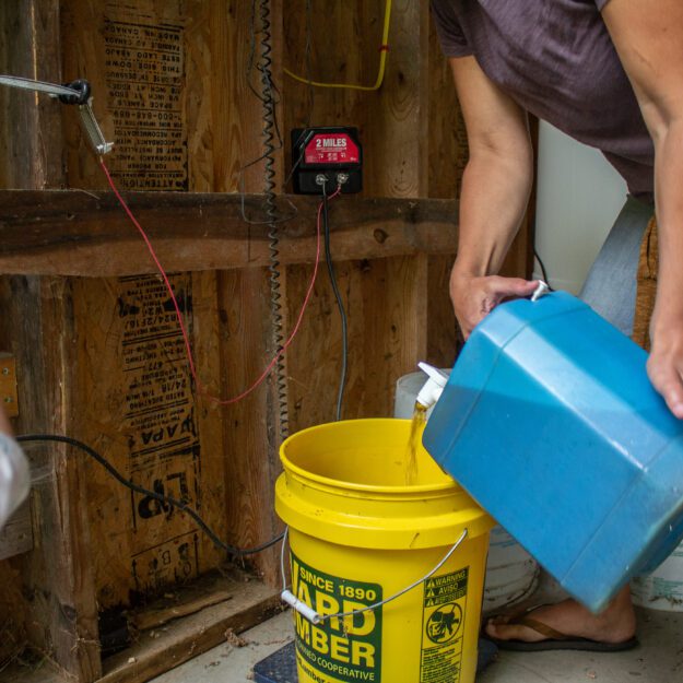 A woman pours human urine into a bucket to be composted