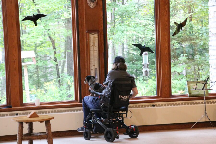 man in a wheelchair with his dog looking out the window at nature during Adirondack Nature Festival for People with Disabilities