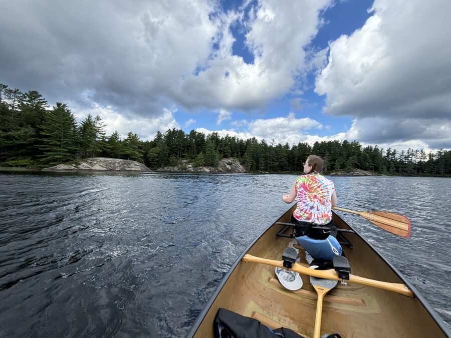 Woman in a tie-dye shirt paddling on the oswegatchie river