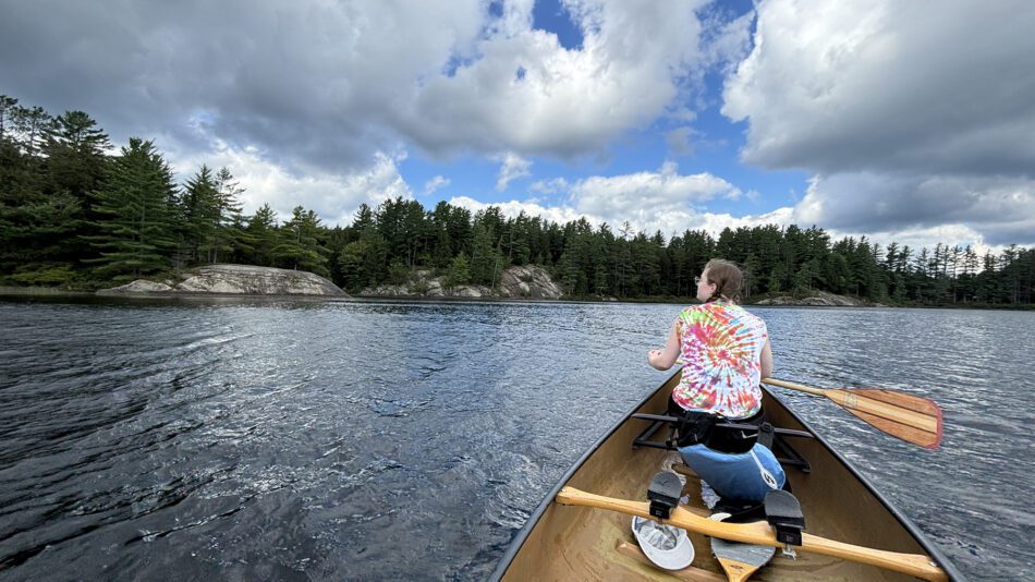 Woman in a tie-dye shirt paddling on a lake