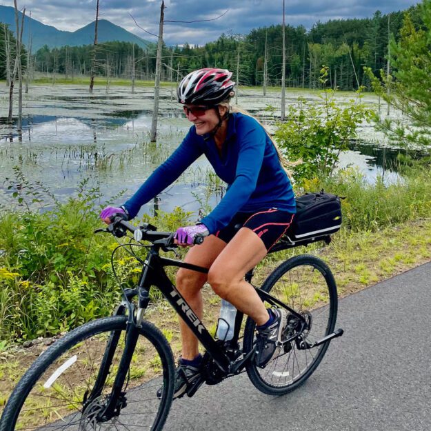 A woman riding a bike on the Placid-to-Saranac segment of the Adirondack Rail Trail