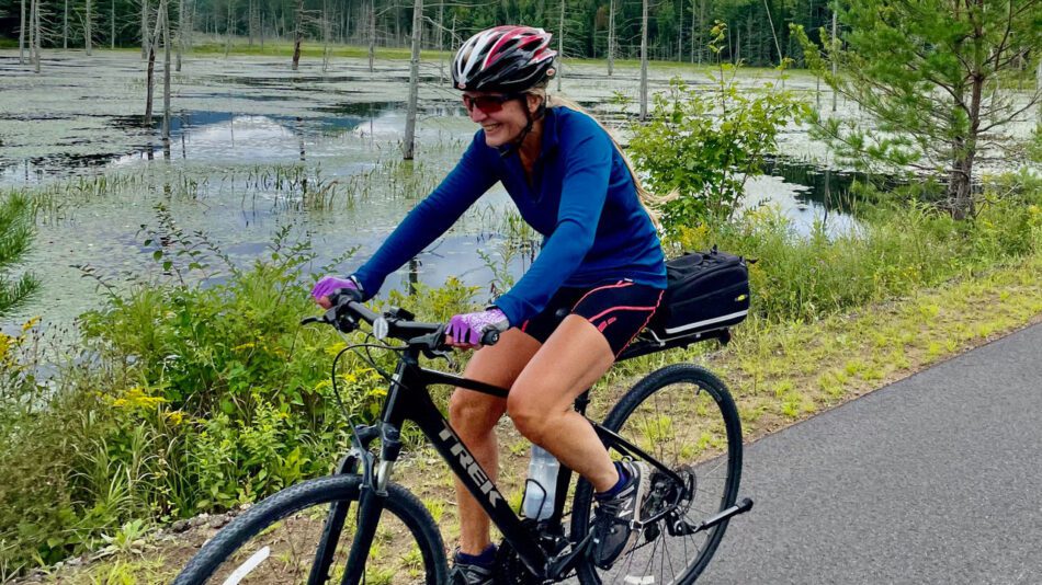 A woman riding a bike on the Placid-to-Saranac segment of the Adirondack Rail Trail