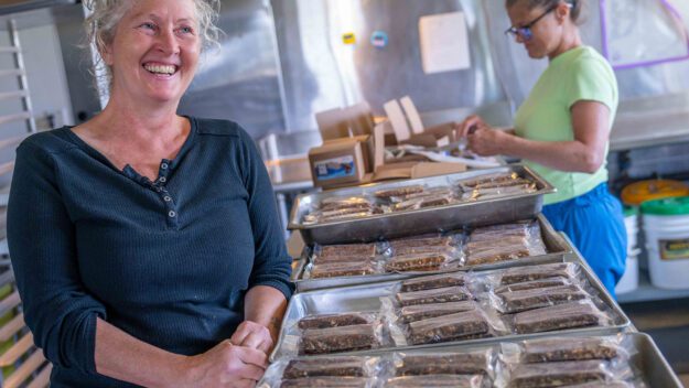 Susie Smith, Founder and President of Dak Bar, wearing a blue shirt, at her production facility at The Hub in Essex.