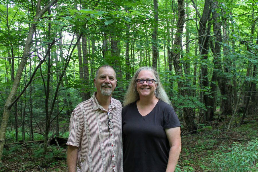 Tim and Janine stand in their green forest in the Adirondacks. They are part of the Family Forest Carbon Program, a partnership of The American Forest Foundation and The Nature Conservancy, targets landowners with at least 30 acres to participate.  