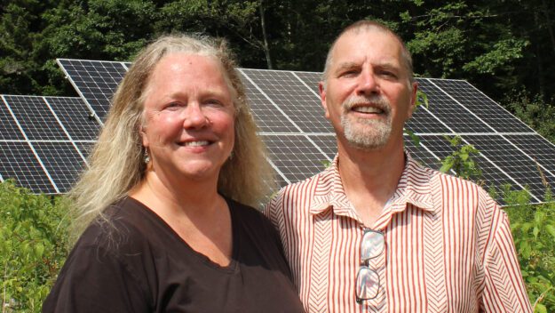 Janine and Tim Van Norman stand in front of solar panels they installed.