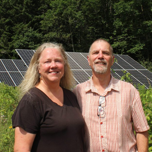 Janine and Tim Van Norman stand in front of solar panels they installed.