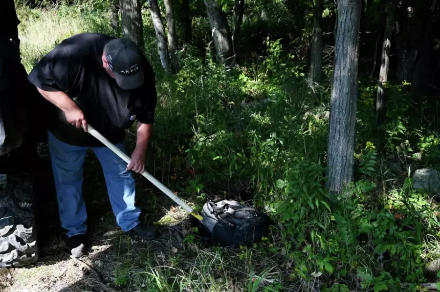 man poking a backpack with a shovel